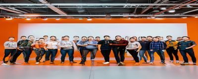 淫男乱女平台新功能上线发布会现场，产品团队在橙色主题背景板前合影，专业感十足